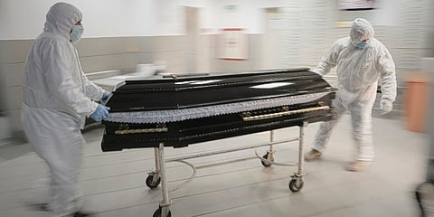 Funeral house employees drag a coffin on a trolley as they arrive at the University Emergency Hospital morgue to take a COVID-19 victim for burial, in Bucharest, Romania. (Photo | AP)