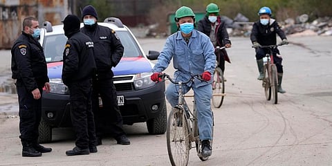 Vietnamese workers who are helping construct the first Chinese car tire factory in Europe ride bicycles past security officers near the northern Serbian town of Zrenjanin, Serbia. (Photo | AP)
