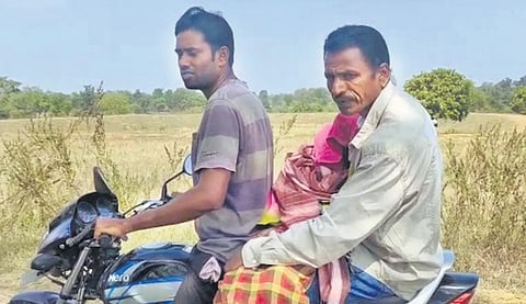 Son and husband of a deceased woman carry her body on a bike in Dharmagarh | Express