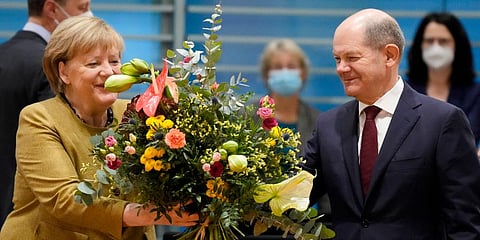 German Chancellor Angela Merkel (L) receives a bouquet from Vice Chancellor and Finance Minister Olaf Scholz (R) prior to the cabinet meeting at the chancellery in Berlin. (Photo | AP)