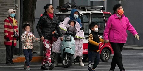 Residents, some wearing masks, cross a road in Beijing, China. (Photo | AP)