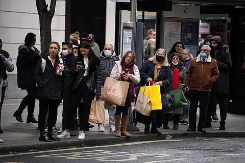 Shoppers wait at a bus stop, where they will be required to wear masks to curb the spread of coronavirus once the get on a bus. (Photo | AP)
