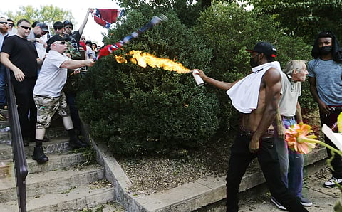 In this Aug. 12, 2017, file photo, a counter demonstrator uses a lighted spray can against a white nationalist demonstrator at the entrance to Lee Park in Charlottesville, Va. (Photo | AP)