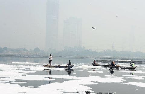 Fishermen wade through toxic foamy waters in the Yamuna at Kalindi Kunj.