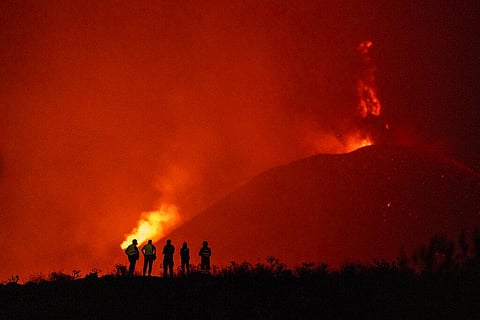 Police officers and emergency personnel look as lava flows from a volcano as it continues to erupt on the Canary island of La Palma, Spain. (Photo | AP)