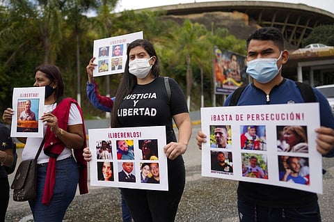 Andreina Baduel wears a T-shirt that reads in Spanish 'Justice and freedom' and holds a sign with pictures of people during a protest against political prisoners outside the SEBIN (Photo | AP)