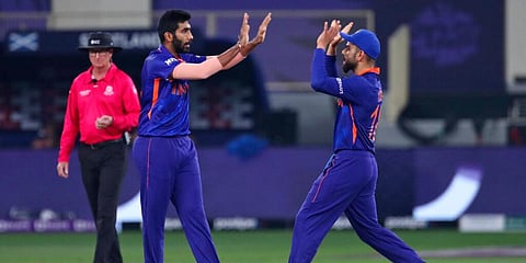 India's Jasprit Bumrah, left, celebrates the dismissal of a Scotland batter with captain Virat Kohli. (Photo | AP)