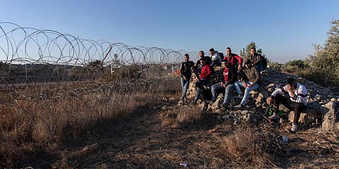 Palestinians gather by a section of Israel's separation barrier, while they wait for the Israeli army to allow them to cross the fence, in the West Bank village of Nilin, Ramallah.