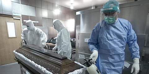 A member of the medical staff disinfects the coffin of a COVID victim at the University Emergency Hospital before funeral house employees take it away for burial, in Bucharest, Romania. (Photo | AP)