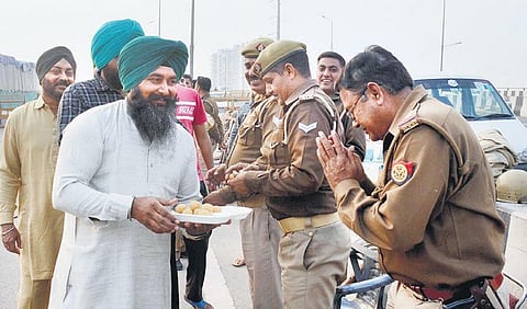 Farmers offer sweets to policemen at Ghazipur border . (Photo| Parveen Negi)