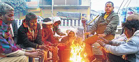 People sit around a bonfire to warm themselves on a winter morning in Gurugram. (Photo | PTI)