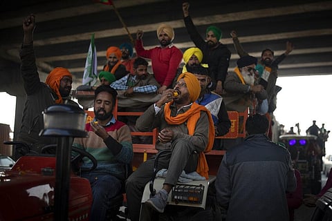 Indian farmers eat sweets as they celebrate while leaving the protest site in Singhu, on the outskirts of New Delhi. (Photo | AP)