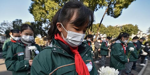 Students wearing face masks hold flowers mourn for the victims of the Nakjing Massacre at a mass burial site during the annual commemoration of the 1937 Nanking Massacre in Nanjing. (Photo | AP)