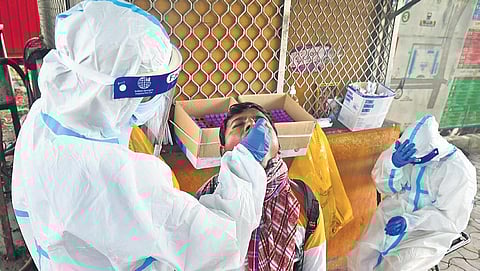 A health worker collects swab of a traveller in Bengaluru on Tuesday. (Photo | Shriram B)