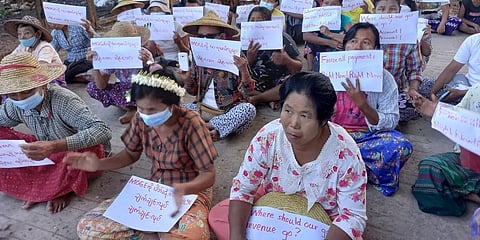 Women sit-in protest in the village of Latpantaung in Myanmar while holding signs calling for the freezing of revenues the Myanmar military gets from the sale of oil and gas. (Photo | AP)