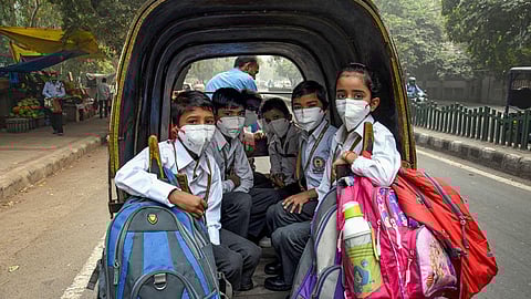 Students wearing masks to get protection from air-pollution go to their school by a rickshaw.