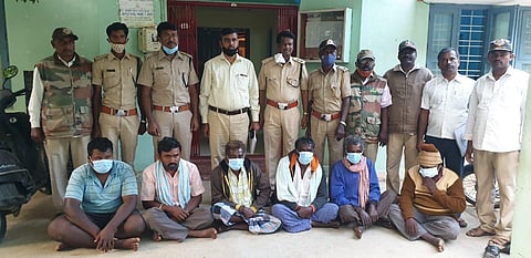 The forest department personnel along with the accused, squatting, who hunted down a sloth bear for game meat.