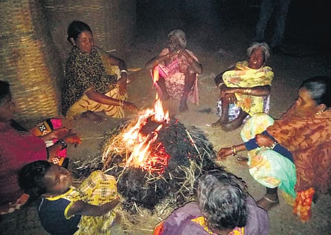 Tribal women gather around a bonfire for warmth in Pottangi | Express