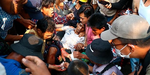 Anti-coup protesters surround an injured man in Hlaing Thar Yar township in Yangon, Myanmar. (Photo | AP)
