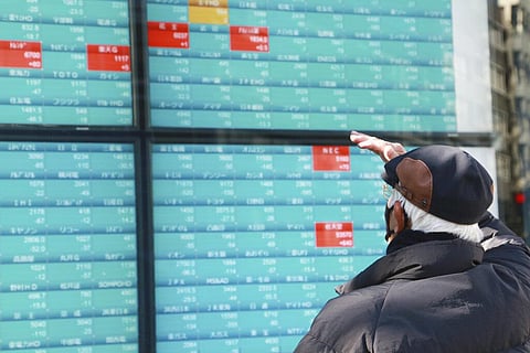 A man looks at an electronic stock board of a securities firm in Tokyo. (Photo | AP)