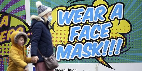 People walk past a billboard inviting citizens to wear face masks to curb the spread of COVID-19, in Nottingham, England. (Photo | AP)