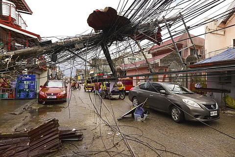 Cars pass by a toppled electrical post due to Typhoon Rai in Surigao city, Surigao del Norte, southern Philippines as power supply remain down . (Photo | AP)