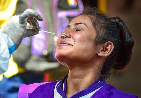 A health worker conducts COVID-19 testing of commuters as 'Omicron' cases cases rise in India, at KSR railway station in Bengaluru. (Photo | PTI)