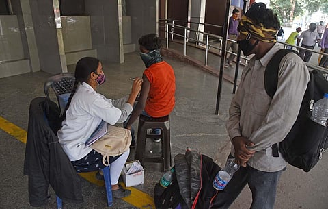 A health worker administers Covid vaccine to a migrant worker at KSR Bengaluru railway station. (Photo | Vinod Kumar T, EPS)