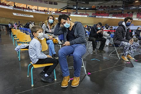 Hugo Chappaz, 9, left, waits with his father Benoit Chappaz, right, and his mother >> Julie Roret to be vaccinated at the National Velodrome in Saint-Quentin-en-Yvelines. (Photo | AP)