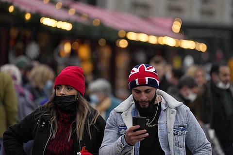 People walk past a Christmas market in Trafalgar Square in London, Wednesday, Dec. 22, 2021. (Photo | AP)