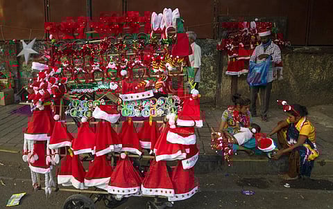 A woman feeds her child on the side of a road, as she waits for customers to buy decorative items for the Christmas from her mobile shop, in Mumbai. (Photo | AP)