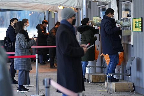 Medical workers in booths take nasal samples from people at a makeshift testing site in Seoul, South Korea. (Photo | AP)