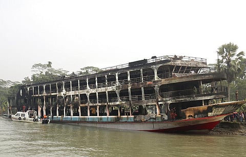 A burnt passenger ferry is seen anchored off the coast of Jhalokati district on the Sugandha River in Bangladesh. (Photo | AP)