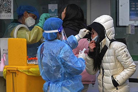 People get a swab for the COVID-19 test for traveling requirement at a mobile coronavirus testing facility outside a commercial office buildings in Beijing, Sunday, Dec. 26, 2021. (Photo | AP)
