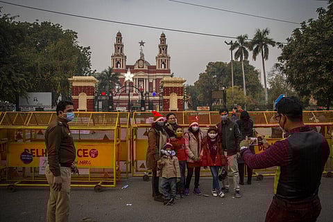 A police officer, left, watches as a family gets their their photograph taken in front of a barricade near the gate of Sacred Heart Cathedral which is closed to general public in Delhi. (Photo | AP)