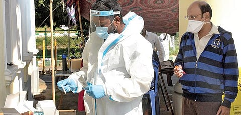 A healthcare worker collects swab samples for Covid-19 testing at Town Hall in Mysuru on Monday | Udayshankar S