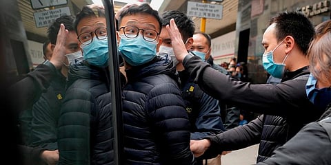 Editor of Stand News Patrick Lam (C) is escorted by police officers into a van after they searched evidence at his office in Hong Kong. (Photo | AP)