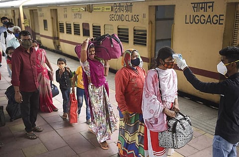 A health worker checks body temperature of passengers as a precaution against the coronavirus, at Dadar Railway Station in Mumbai, Tuesday, Nov. 30, 2021. (Photo | PTI)