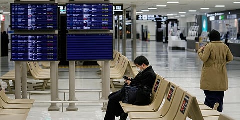 A passenger rests near arrival information screens for international flights at the Narita International Airport in Narita, east of Tokyo. (Photo | AP file)