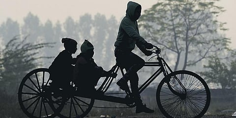 A man rides a tri-cycle during a cold winter morning in New Delhi.