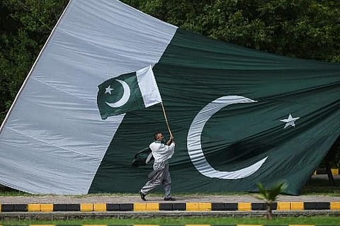 A man holds a national flag of Pakistan as he walks along a street in Islamabad on August 10, 2021. (Representational image | AFP)