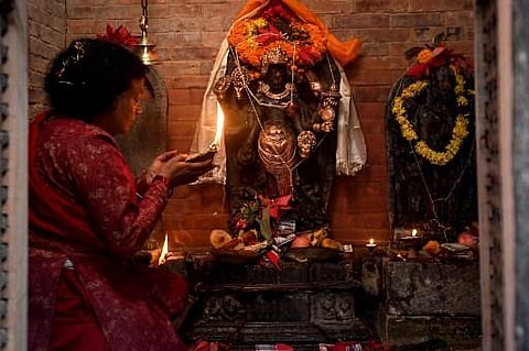 A devotee performs a prayer ritual after a centuries-old sculpture of a Hindu god was re-installed at its temple in Patan (Lalitpur) on the outskirts of Kathmandu. (AFP)