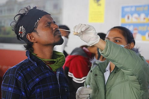 A health worker takes a swab sample of a passenger entering the city to test for COVID-19 at a railway station in Ahmedabad, India, Friday, Dec. 3, 2021. (Photo | AP)