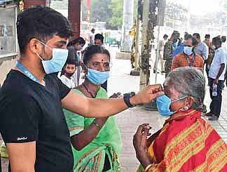 A health worker at Kempegowda bus station adjusts the mask of an elderly woman in Bengaluru on Friday | Shriram BN