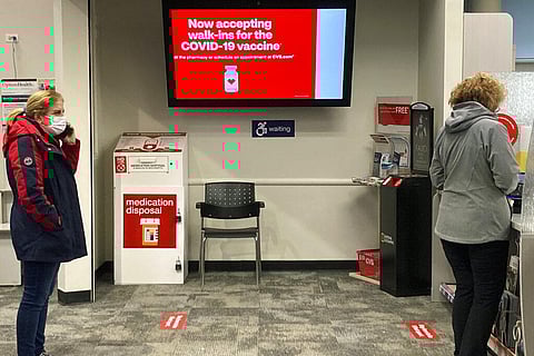 A sign about COVID-19 vaccine is displayed inside of a CVS store as people wait to check in for the vaccine in Buffalo Grove, Ill. (Photo | AP)