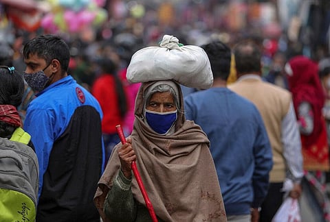 An elderly Indian woman wearing face mask as a precaution against the coronavirus walks at a Sunday market in Jammu. (Photo | AP)