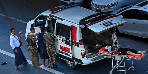An injured protester lies on a stretcher beside an ambulance after a crackdown on the anti-coup demonstration by security forces in Yangon. (Photo| AFP)