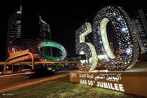 A sign marking the United Arab Emirates' 50th jubilee is lit up along the side of the Sheikh Zayed Road in Dubai on December 1, 2021. (Photo | AFP)