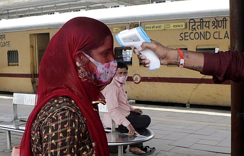 A health worker checks the body temperature of a passenger arriving at a railway station as a precaution against COVID-19 before allowing her to enter the city, in Mumbai. (Photo | AP)