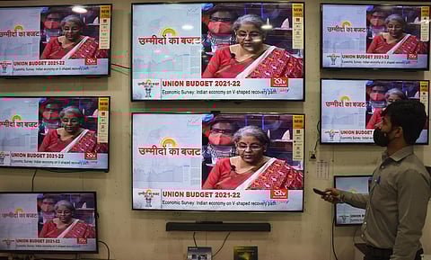 A man seen watching the live broadcat of budget news at a TV Showroom in Coimbatore city on Monday. (Photo | U Rakesh Kumar, EPS)